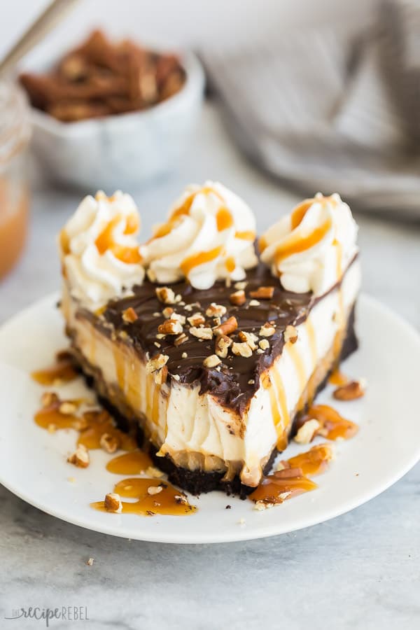 turtle cheesecake slice with whipped cream, caramel and pecans with bite missing
