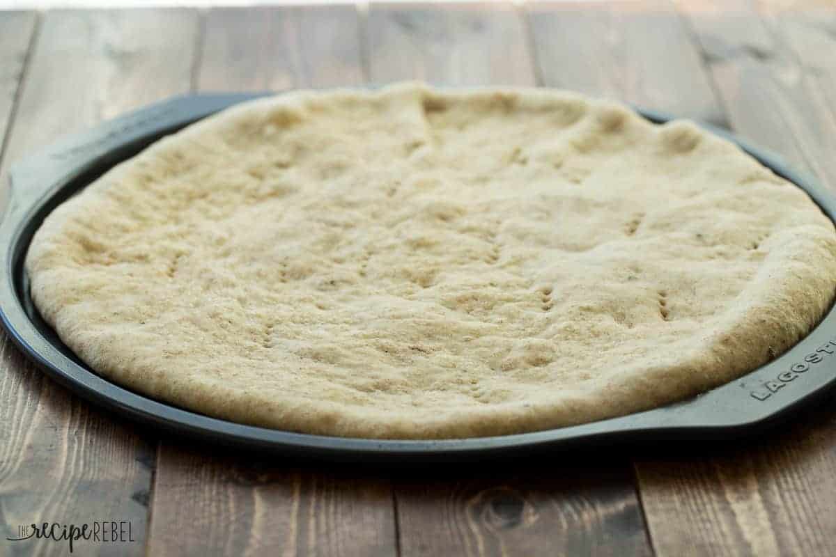 par baked pizza dough on pizza pan on wooden background