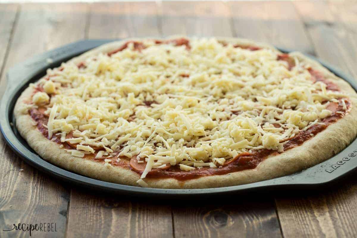 par baked pizza crust with tomato sauce pepperoni and cheese