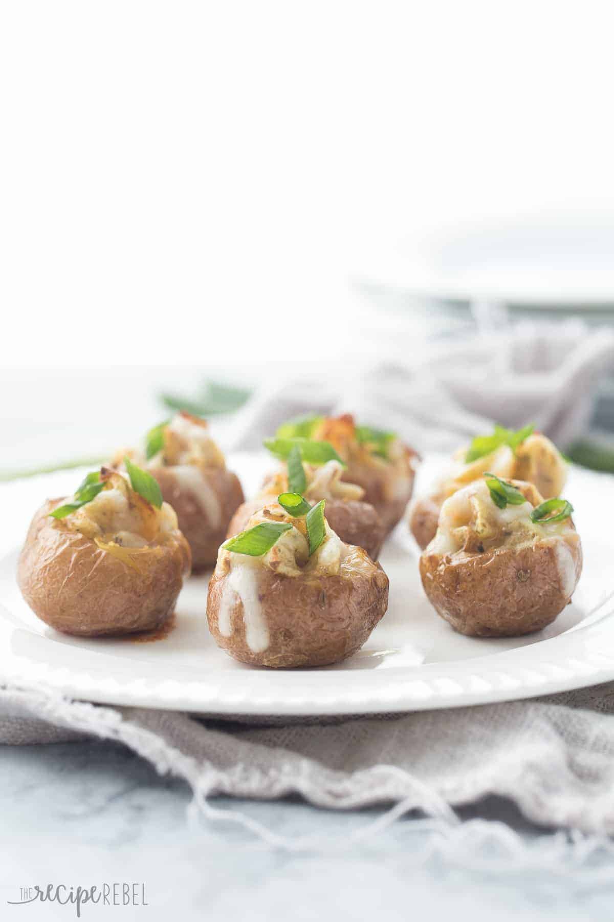 mini twice baked potatoes topped with green onions on a white plate