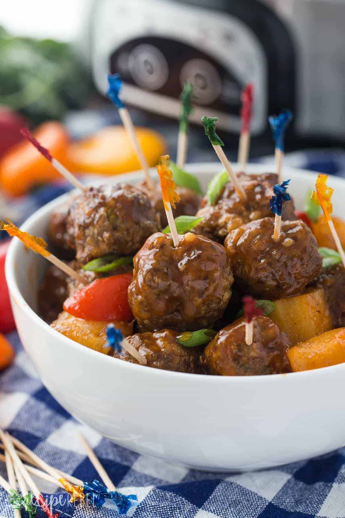 white bowl with pineapple brown sugar meatballs with toothpicks stuck in meatballs