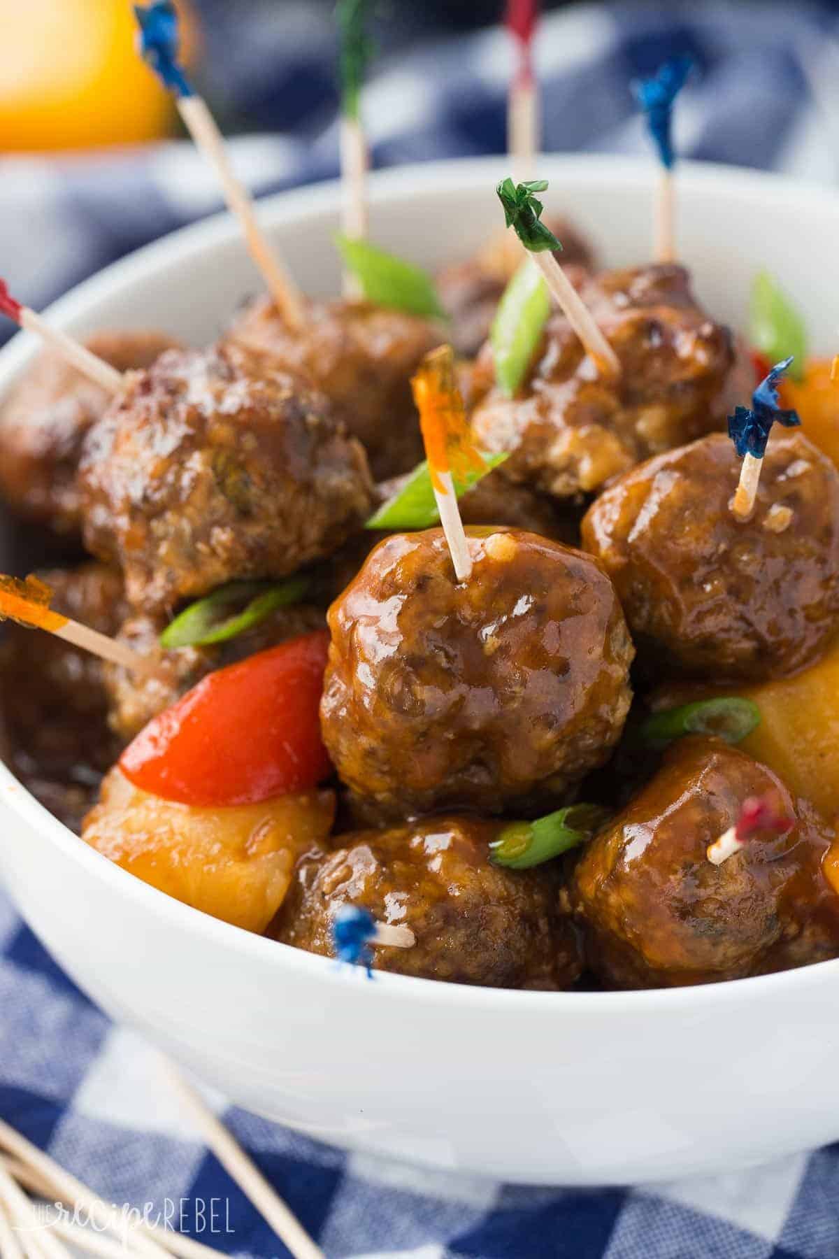 slow cooker pineapple brown sugar meatballs in a white bowl with fancy toothpicks stuck in the meatballs