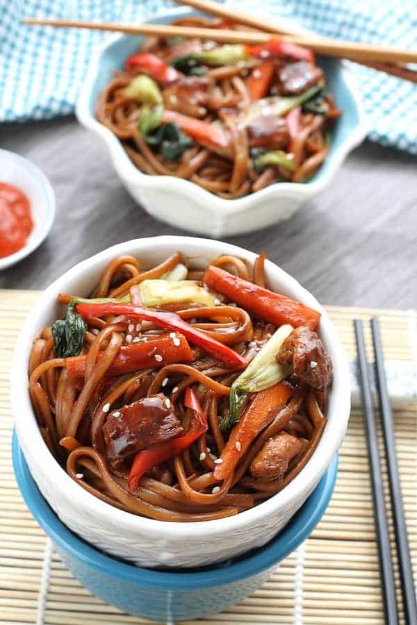 slow cooker chicken lo mein in white bowl with peppers and chopsticks on the side