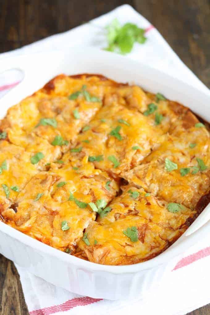 chicken enchilada casserole in white baking dish cut in 6 pieces