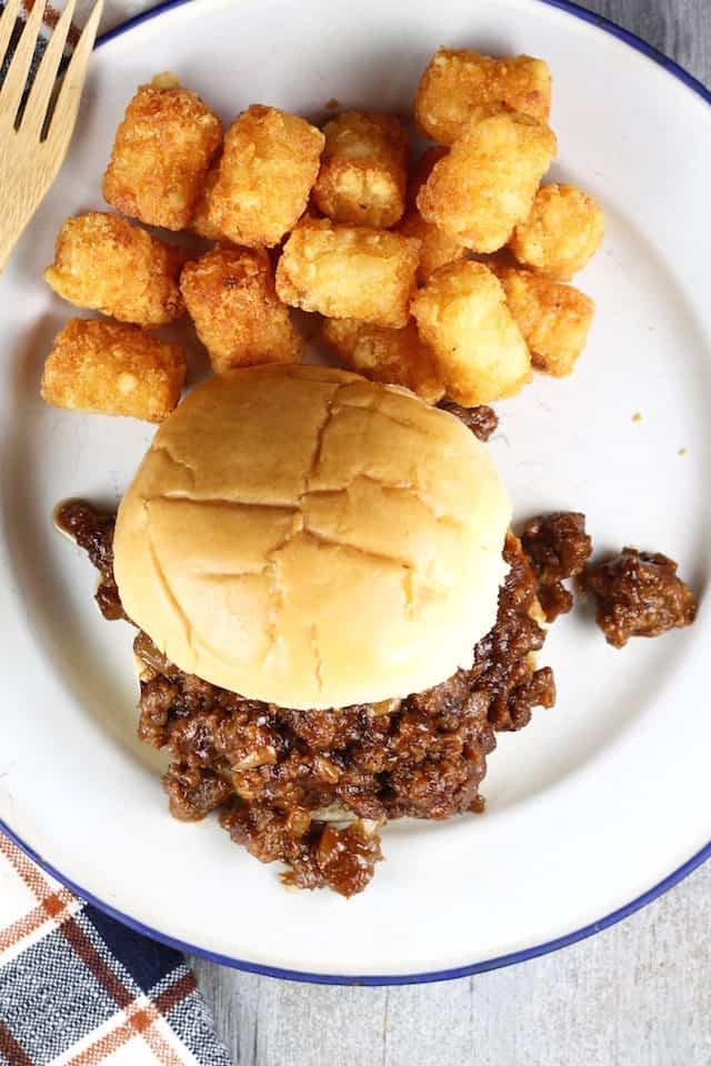 a white plate with dr pepper barbecue sloppy joes on a bun and tater tots