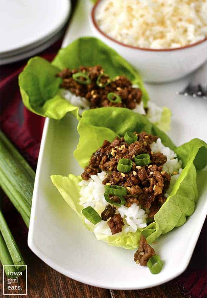 korean beef lettuce wraps on white plate with rice and topped with green onions