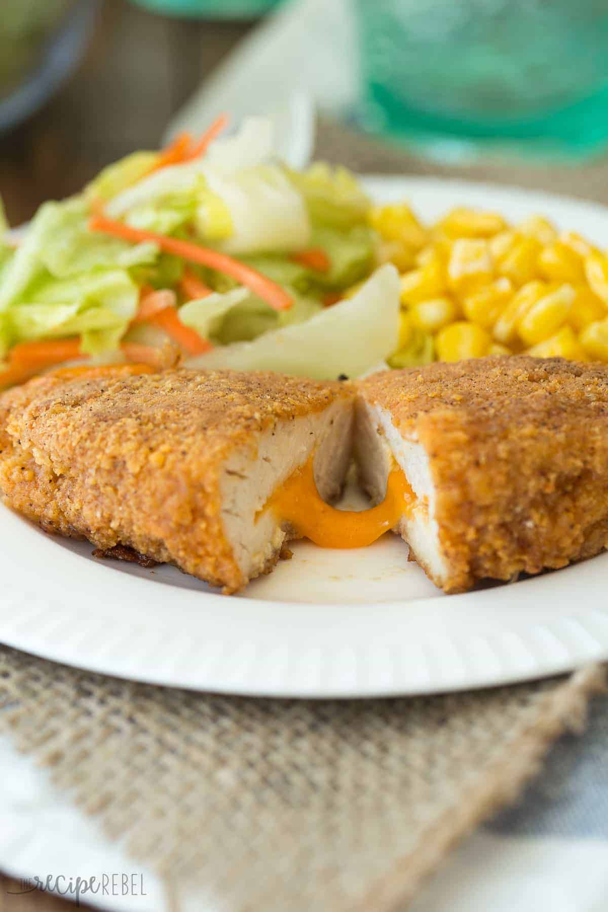 nacho cheese oven fried chicken on white plate with salad and corn cut in half to reveal cheese