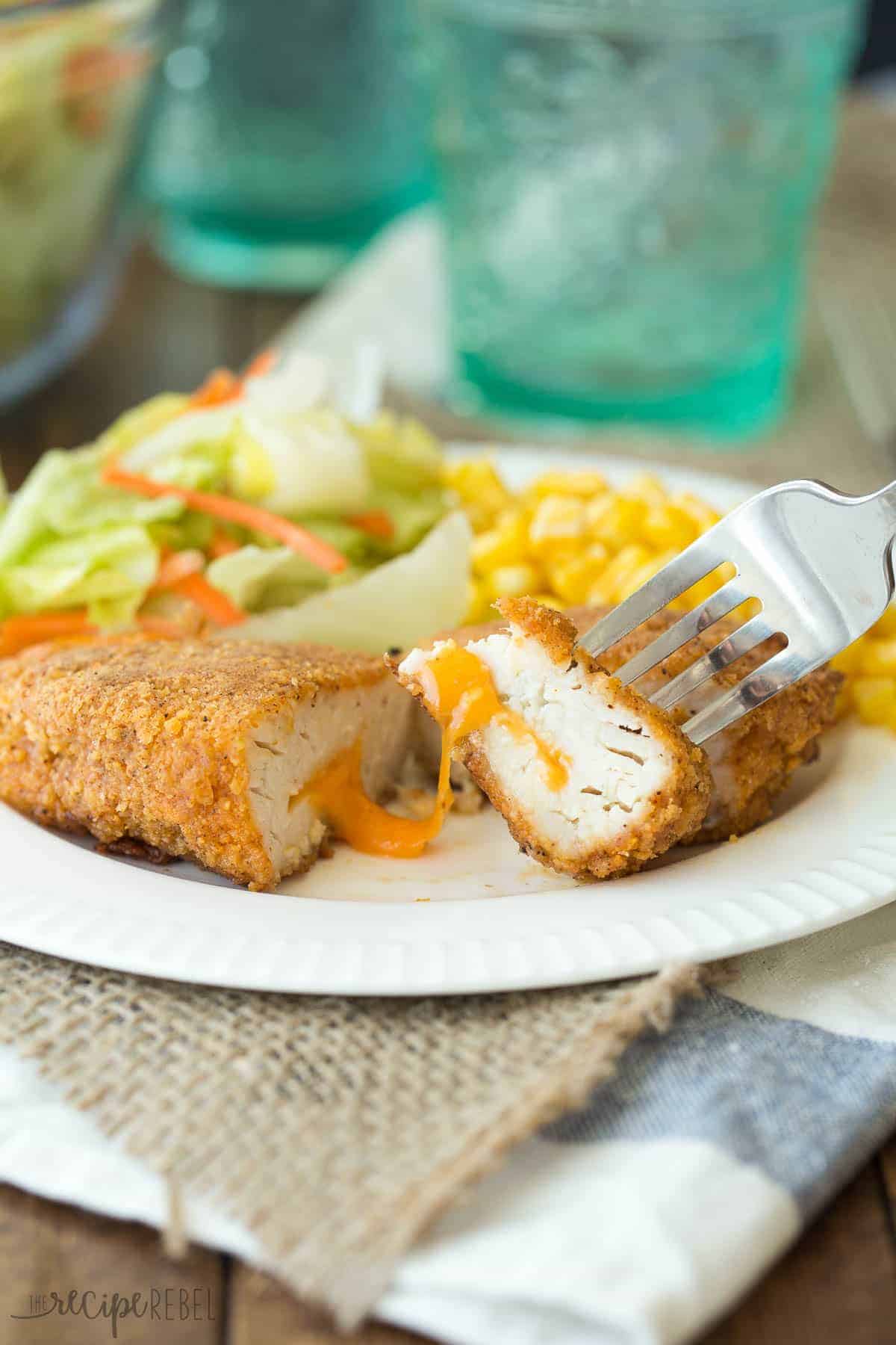 piece of nacho cheese oven fried chicken on fork on white plate with corn and salad