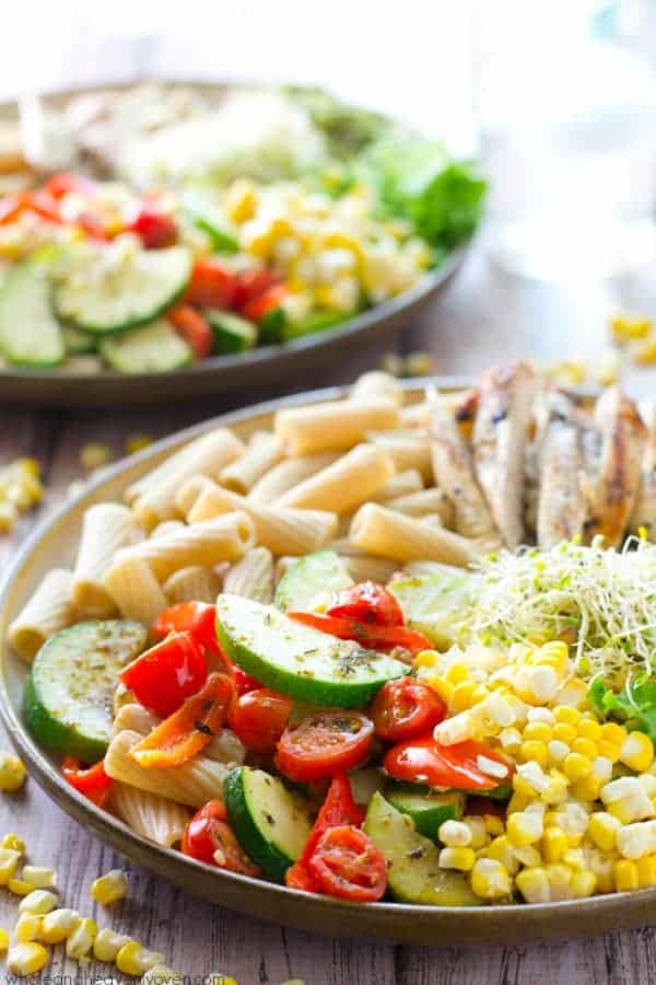 grilled chicken veggie pasta bowls close up with corn zucchini tomatoes and chicken