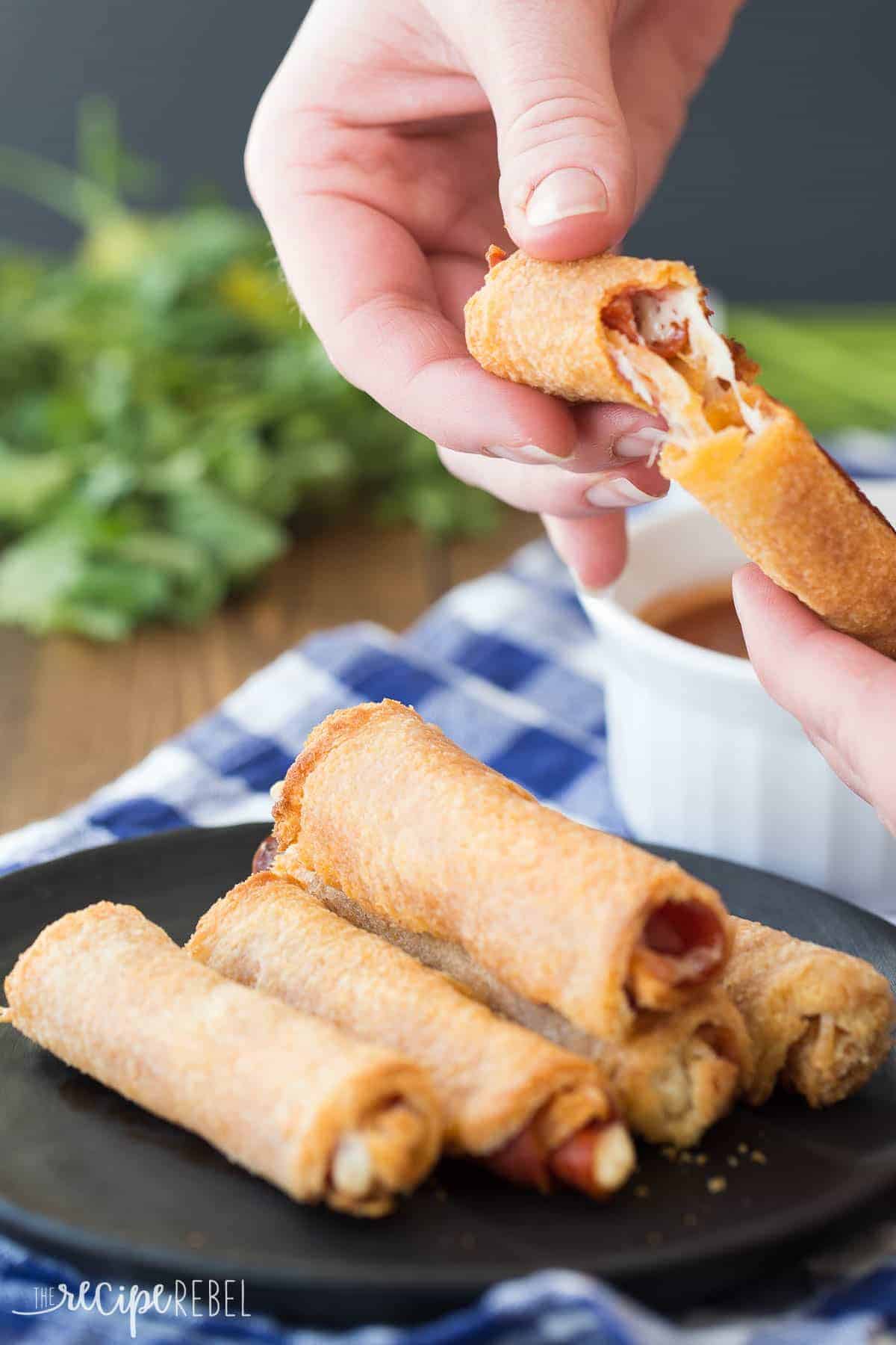 hands pulling apart pizza roll up over top of black plate