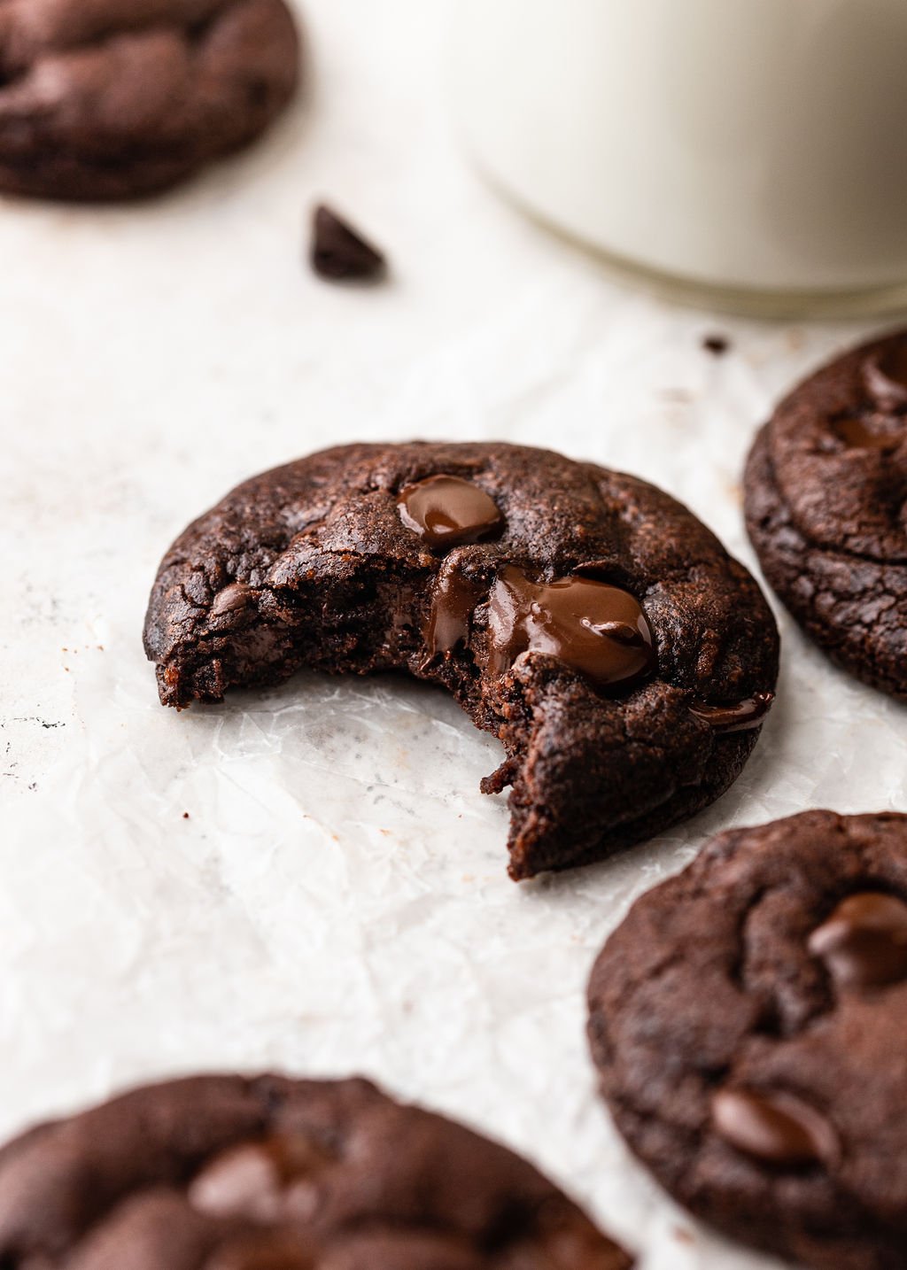 one double chocolate cookie on parchment with a bite missing.