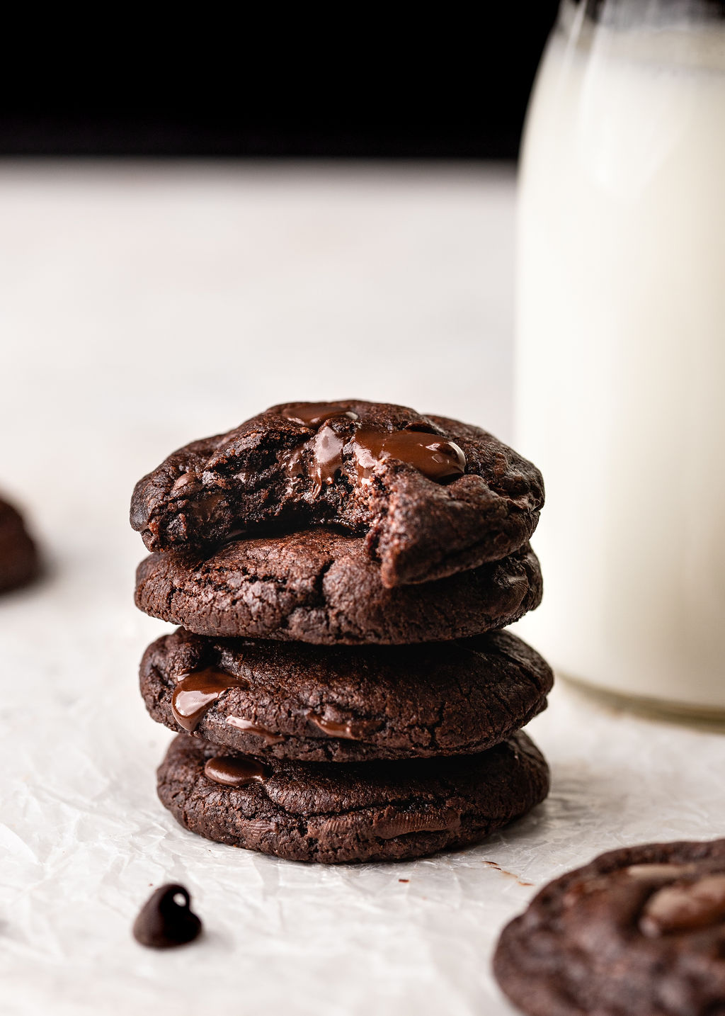 stack of double chocolate cookies with milk in the background.