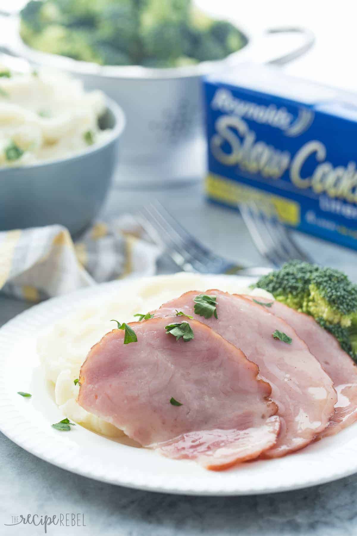 close up of sliced honey glazed ham over mashed potatoes with fresh parsley
