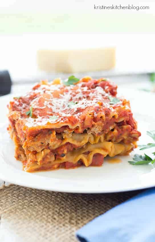 easy slow cooker lasagna piece on white plate with shredded parmesan on top