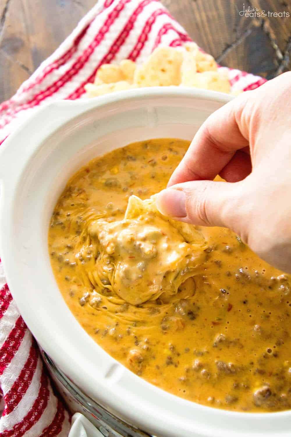 crockpot cheesy hambuger dip in white crockpot with chip dipping 