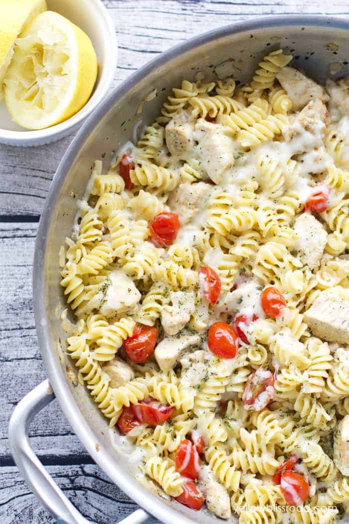 spicy lemon chicken pasta with tomatoes in large steel skillet