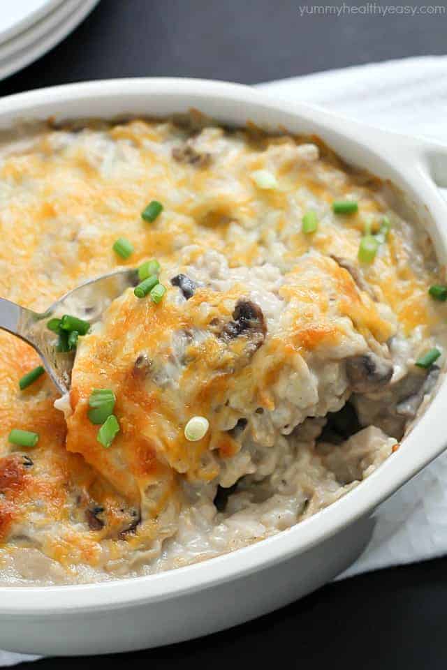 skinny chicken rice casserole in white baking dish with spoon scooping