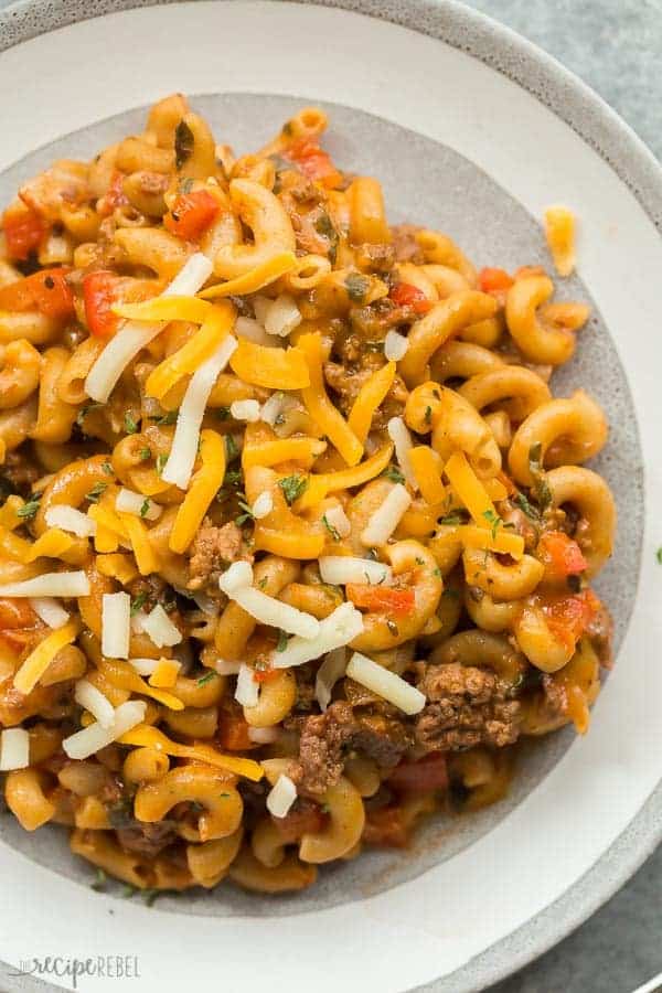 slow cooker hamburger helper on grey plate close up with shredded cheese on top