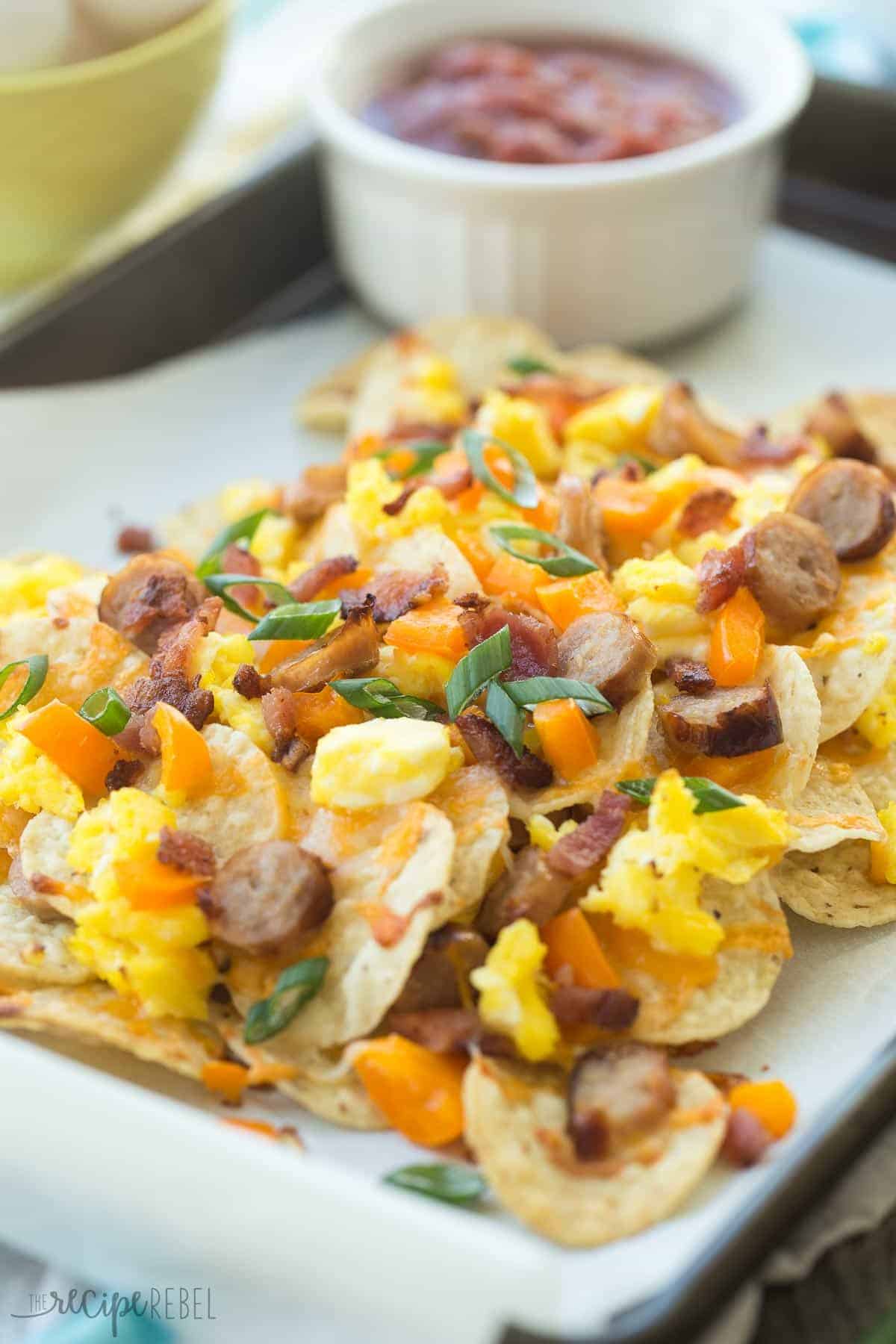 close up image of breakfast nachos with scrambled eggs sausage bacon peppers and green onions