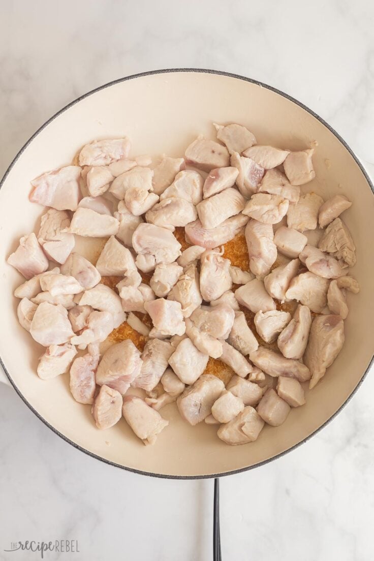 cubed chicken cooking in white skillet