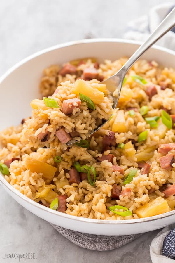 ham and pineapple rice scoop out of white pan on metal spoon