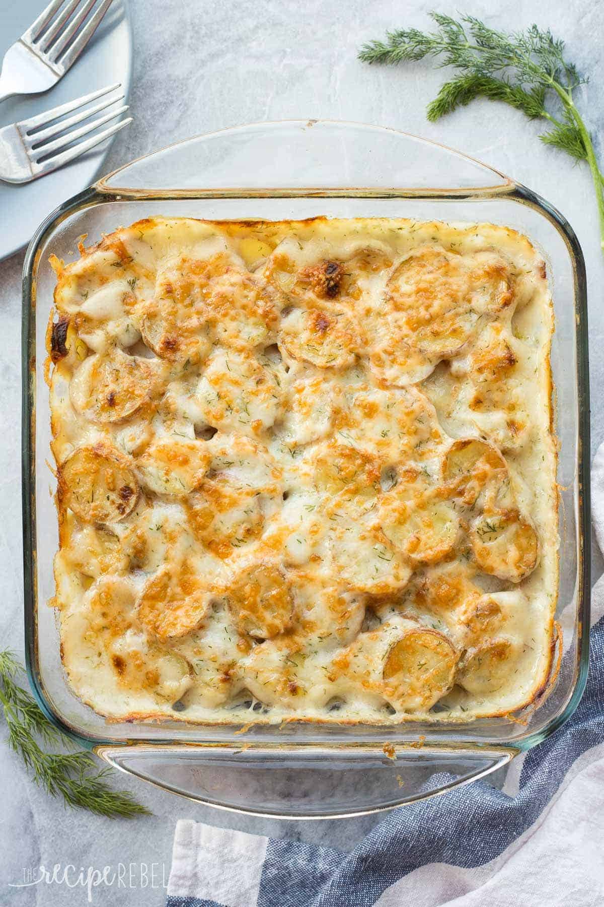 These Light Creamy Dill Scalloped Potatoes have a fraction of the fat as regular scalloped potatoes but you'd never know! Not a fan of dill? Substitute herbs of your choice! overhead image of dill scalloped potatoes in glass baking dish on grey marble