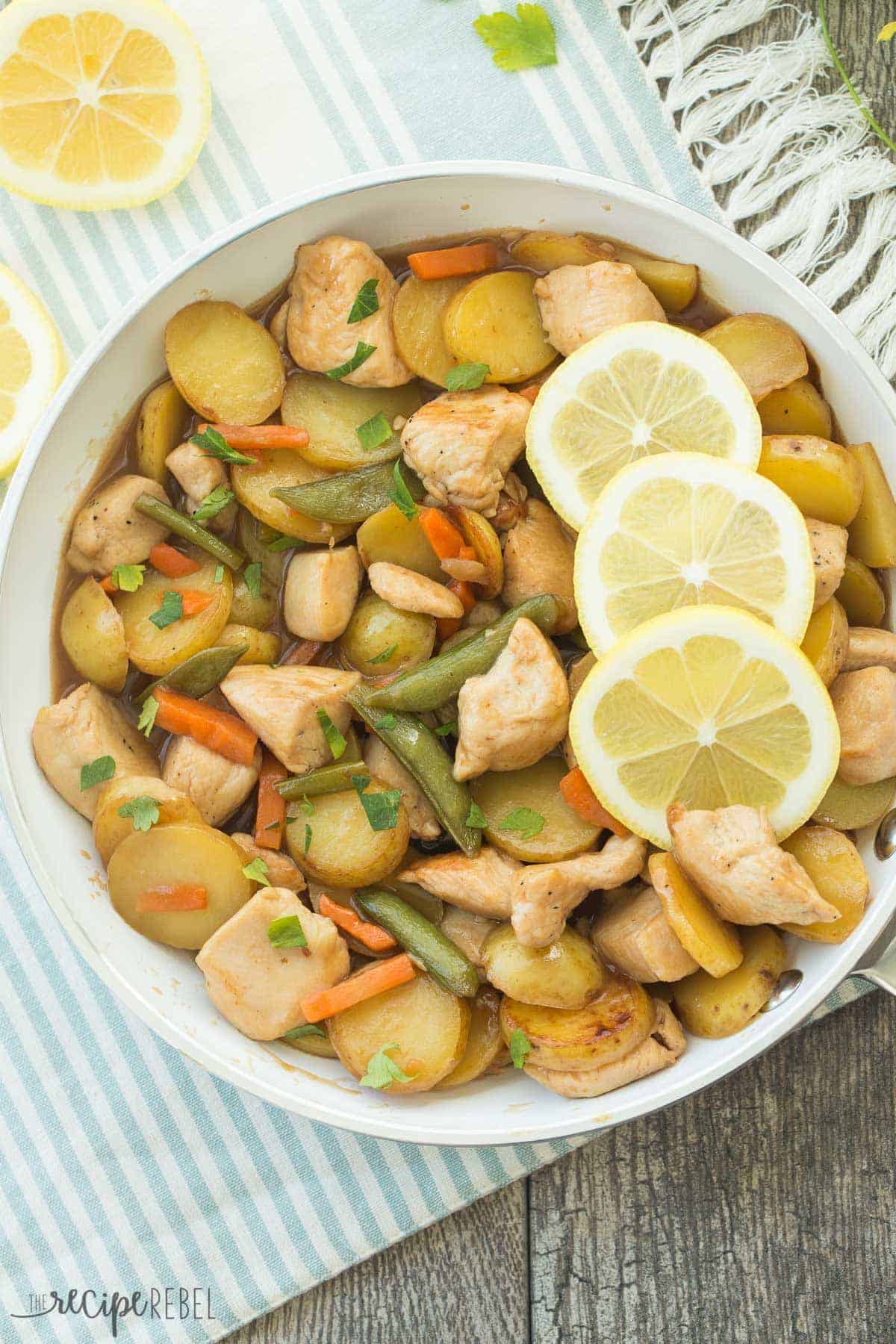 honey lemon chicken and potato skillet in white pan with fresh lemon slices