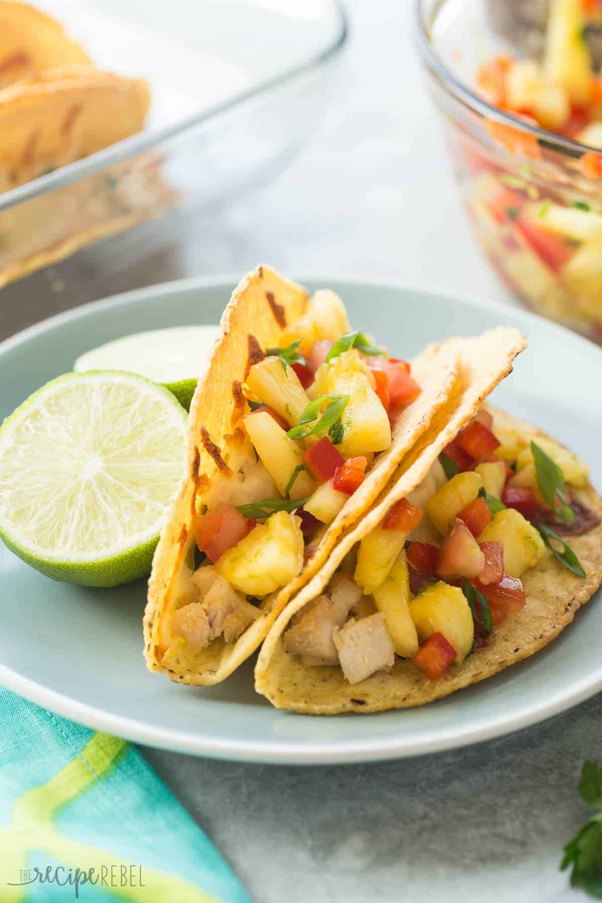 blue plate with two baked chicken tacos with fresh pineapple salsa and green onions