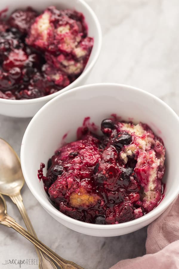 slow cooker berry cobbler in white bowls with spoon