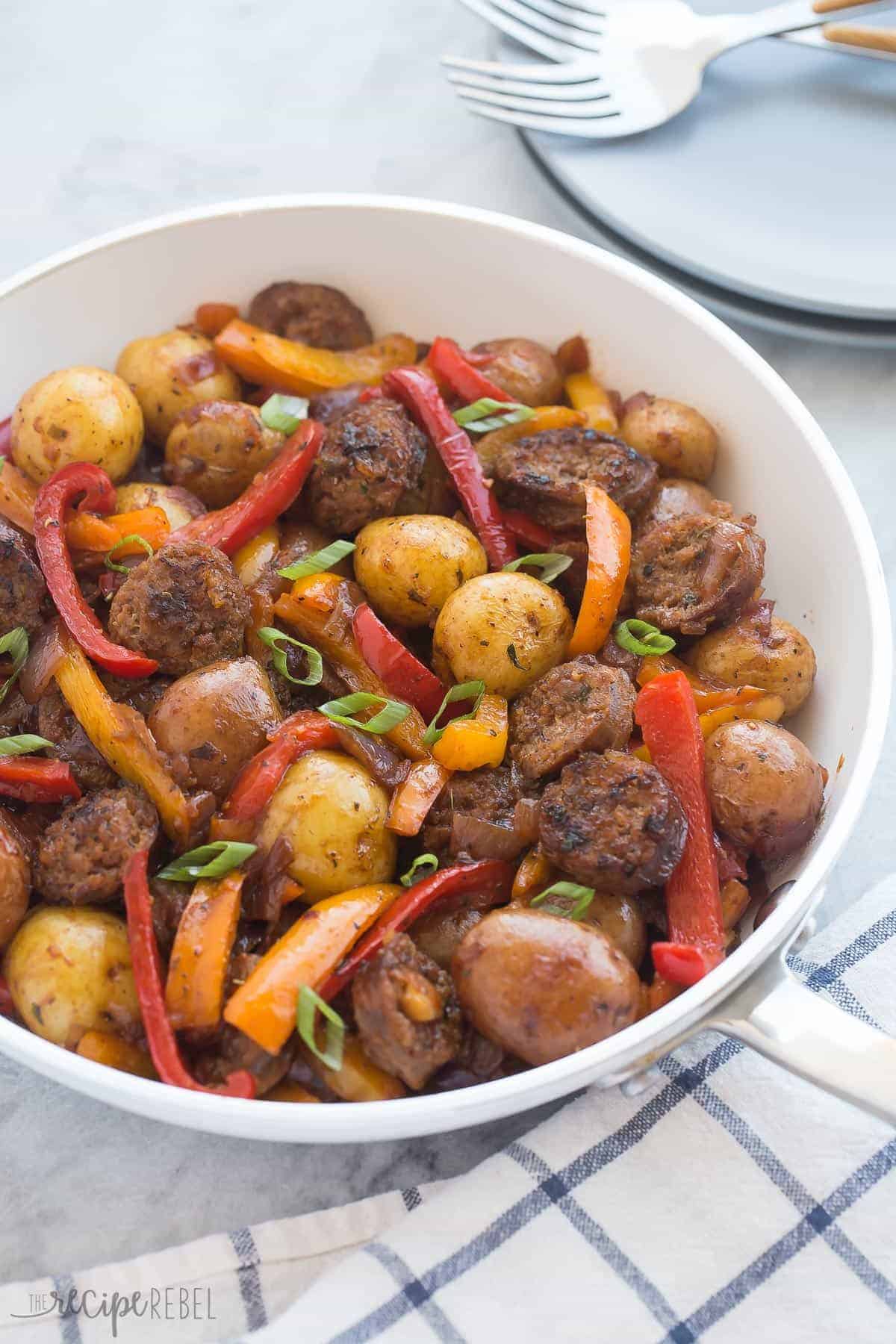 one pot sausage and peppers in white skillet with green onions