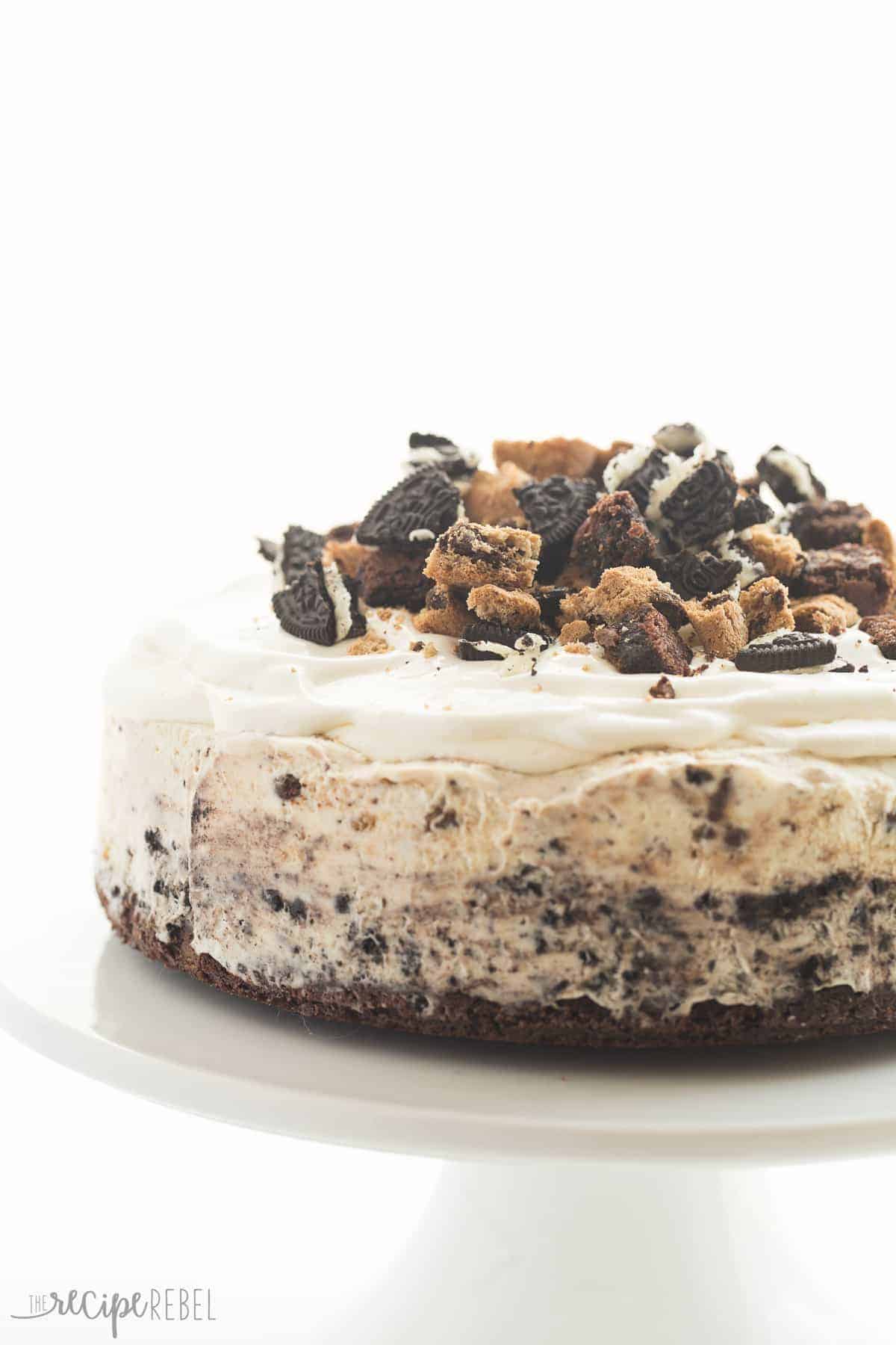 whole chocolate chip cookie oreo brownie ice cream cake on white cake plate with whipped cream