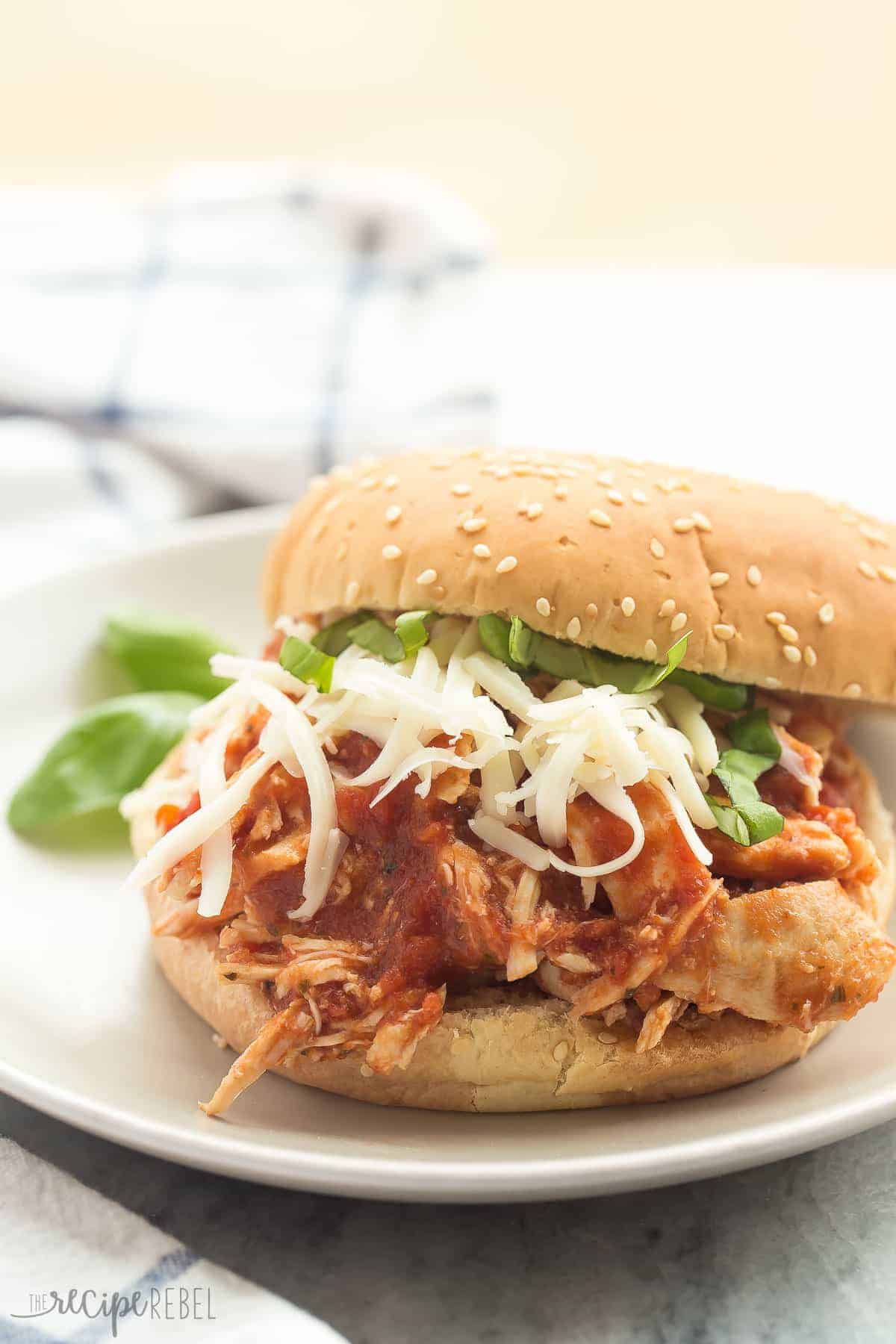 These Dump and Go Slow Cooker Recipes require no cooking or browning beforehand -- simply throw it in and walk away! Easy crock pot dump meals for busy weeknights and back to school! Chicken, beef, pork, or vegetarian -- there's something for everyone! #slowcooker #crockpot #dinner #recipes slow cooker italian chicken sandwiches on a white bun with shredded mozzarella