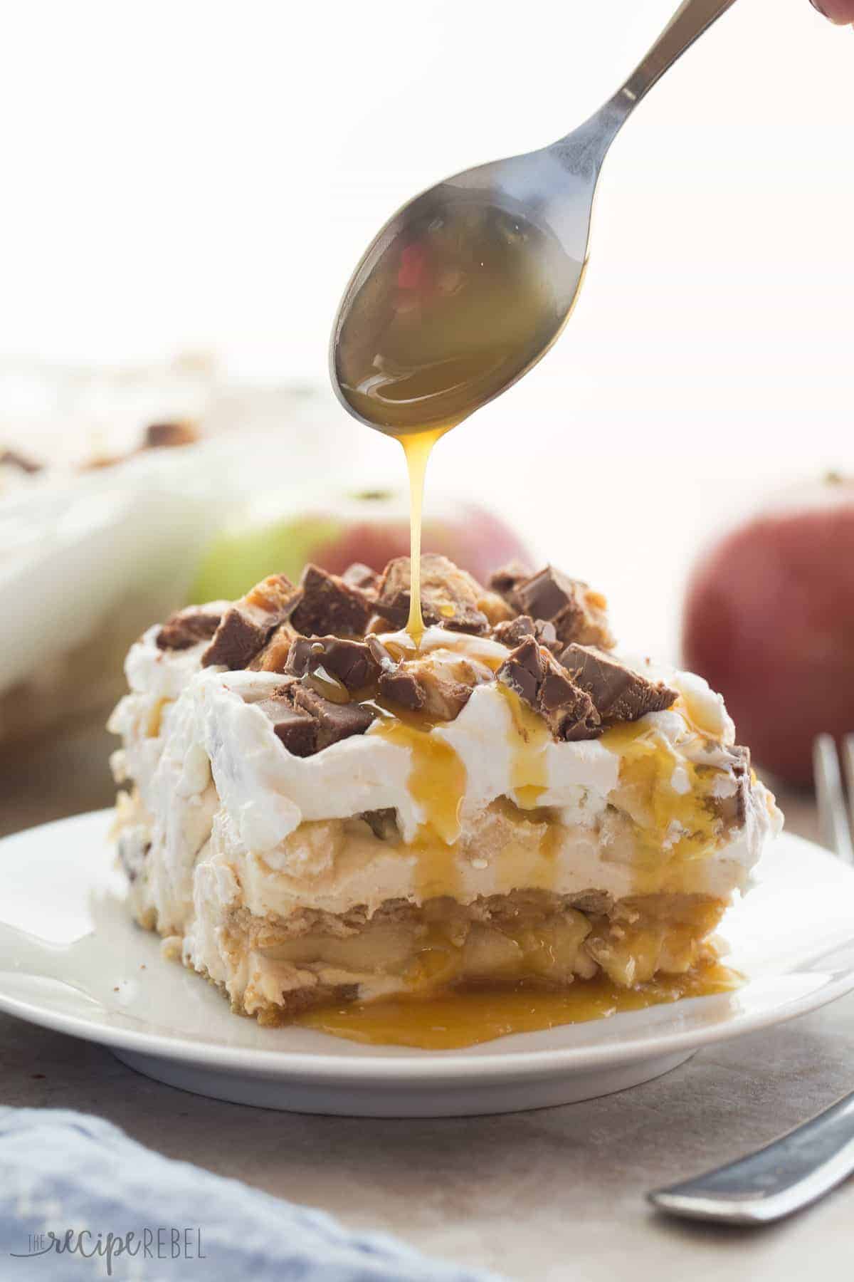 snickers apple icebox cake on white plate being drizzle with caramel sauce from a spoon