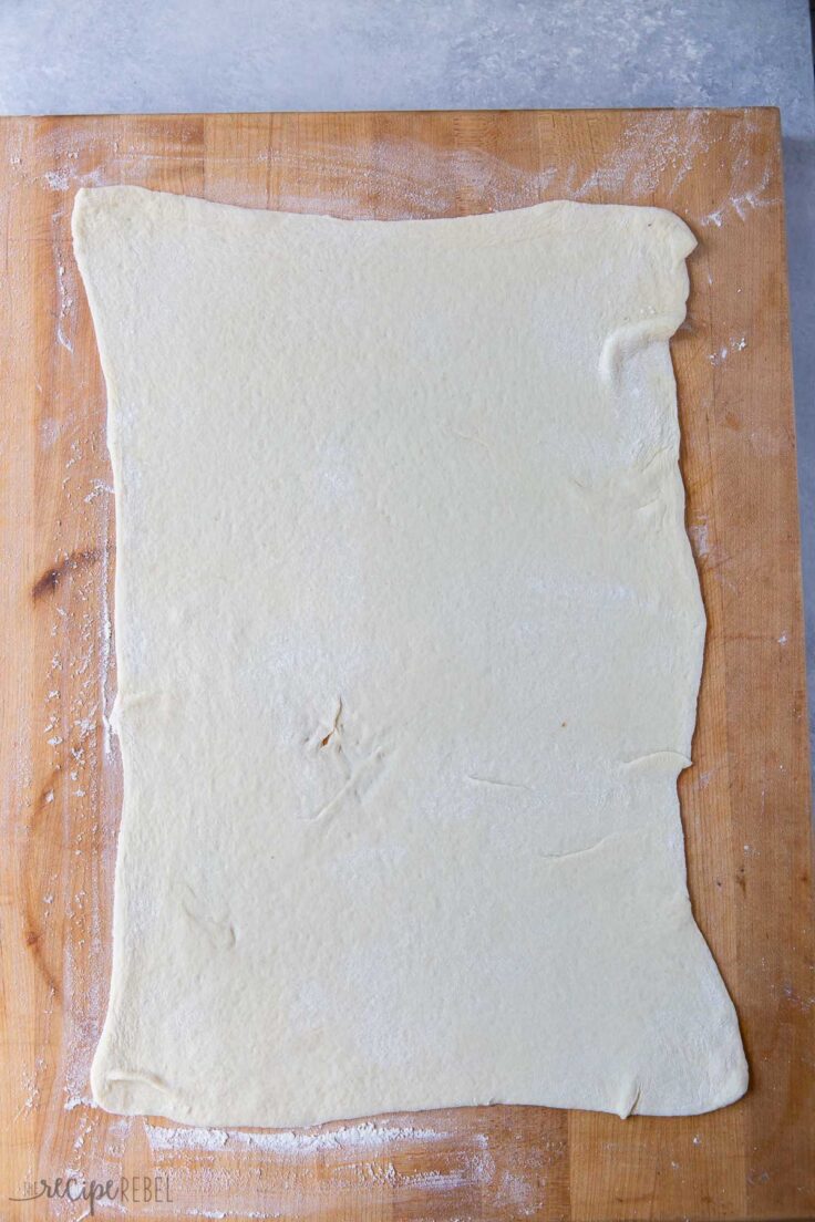 pizza dough rolled out on wooden board