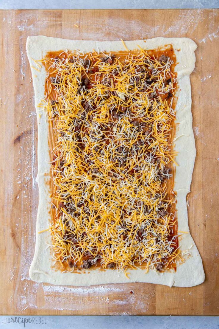 cheese sprinkled on rolled out pizza dough with ground beef and sauce