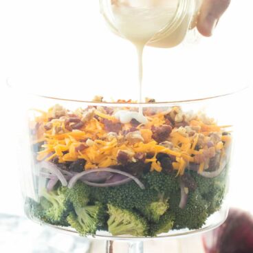 My husband's FAVORITE! This Layered Broccoli Salad is loaded with cheddar cheese, raisins, cranberries, bacon and walnuts and served with a sweet and tangy dressing!