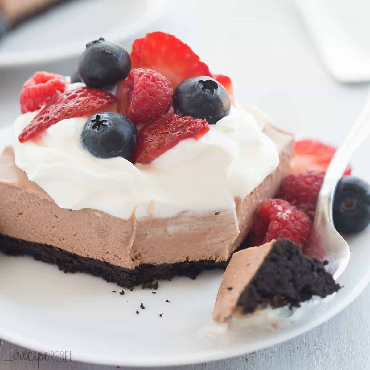 no bake nutella cheesecake bars on white plate with fork taking a bite