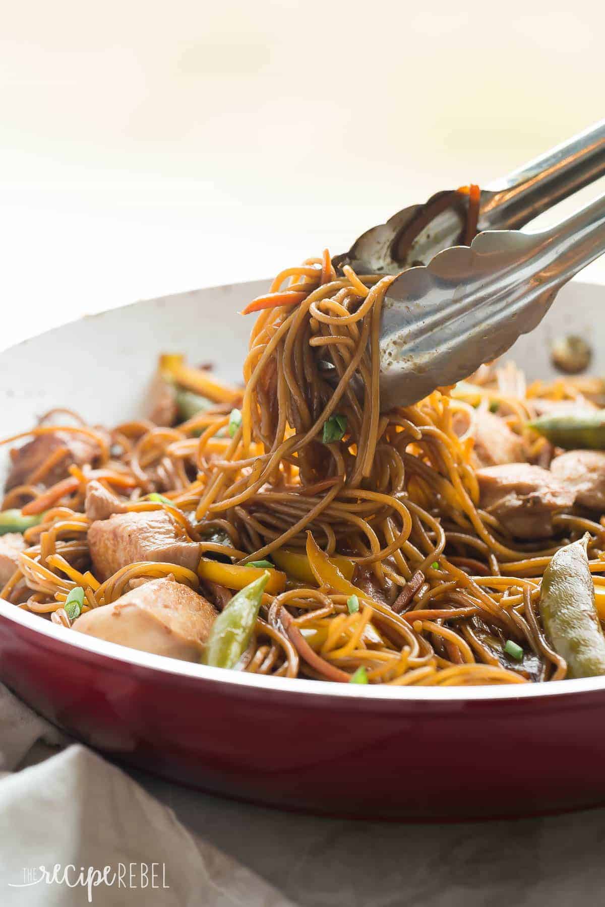 This easy, One Pot Teriyaki Chicken and Noodles is better than any takeout! It's healthier and loaded with veggies, with fewer dishes to wash! PLUS a step by step video! https://www.thereciperebel.com/one-pot-teriyaki-chicken-and-noodles/ teriyaki chicken and noodles in red and white skillet with metal tongs pulling up noodles