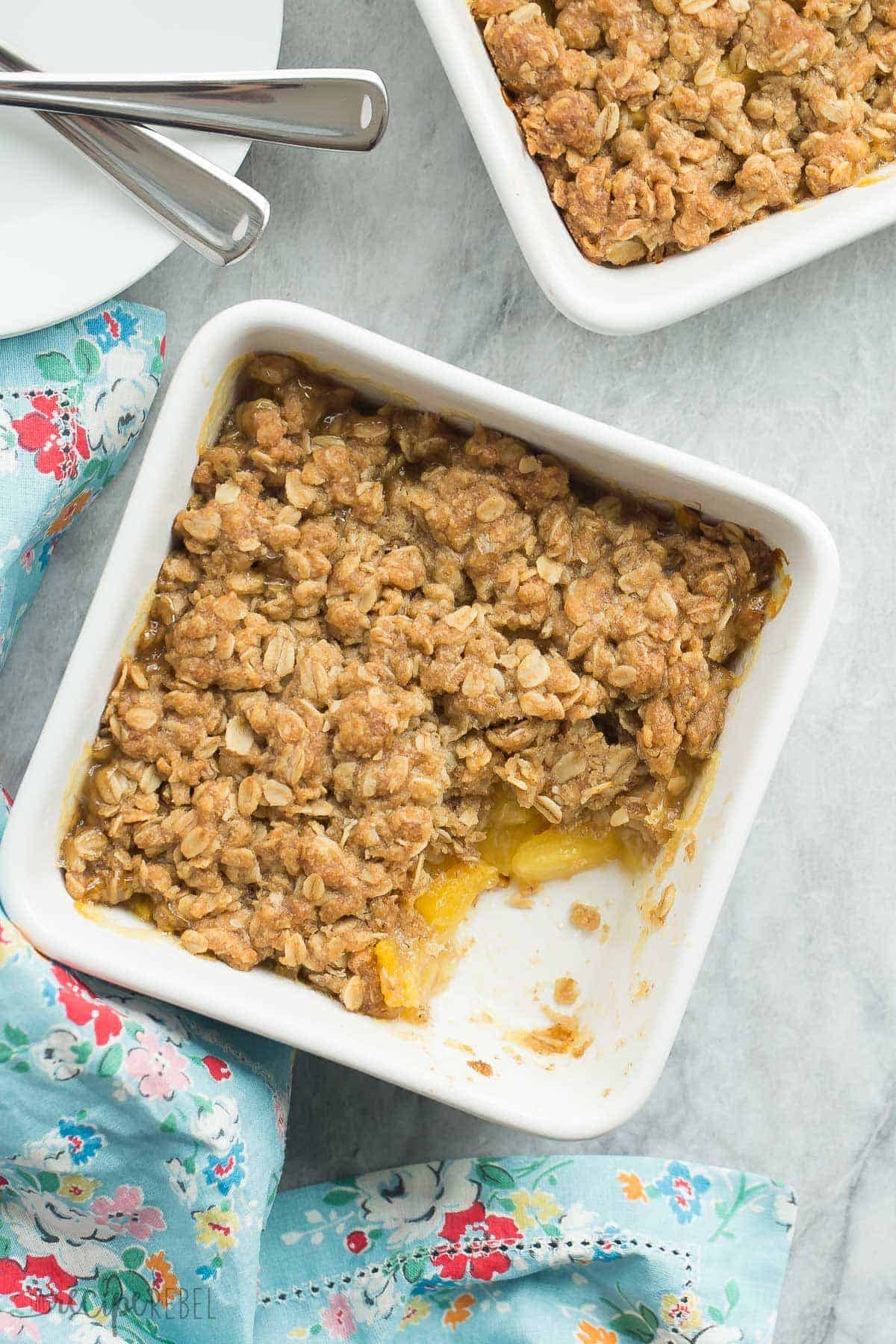 overhead image of square white individual baking dishes with pineapple crisp on grey background