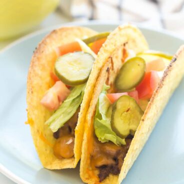 These Cheeseburger Baked Tacos are our new FAVORITE tacos! Filled with barbecue ground beef, cheddar cheese, and topped with all your favorite burger toppings! They're also naturally gluten-free.