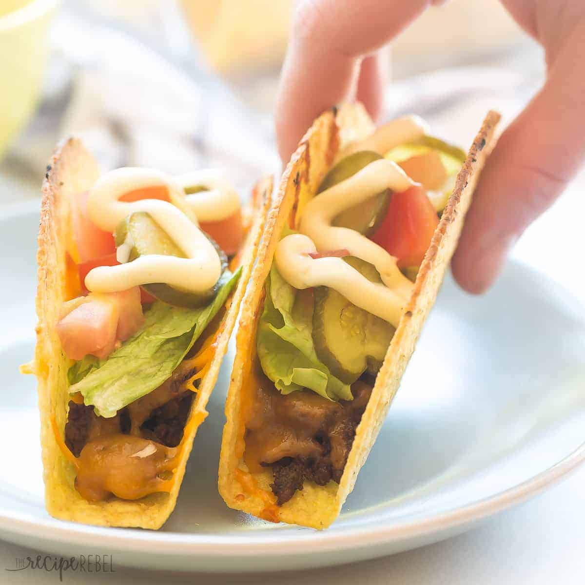 hang grabbing cheeseburger baked taco with lettuce pickles tomato and mayo drizzle