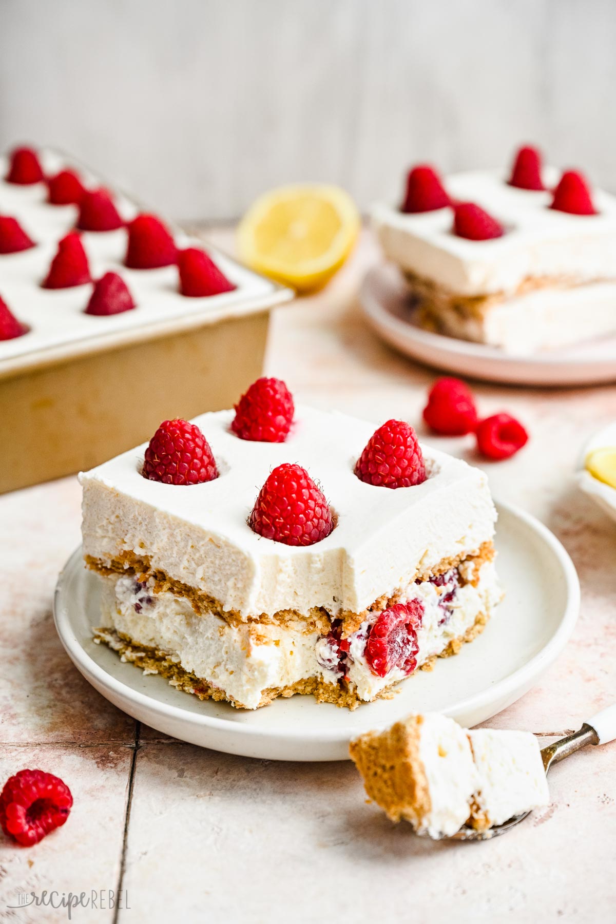 two pieces of lemon icebox cake on plates with pan in the background.