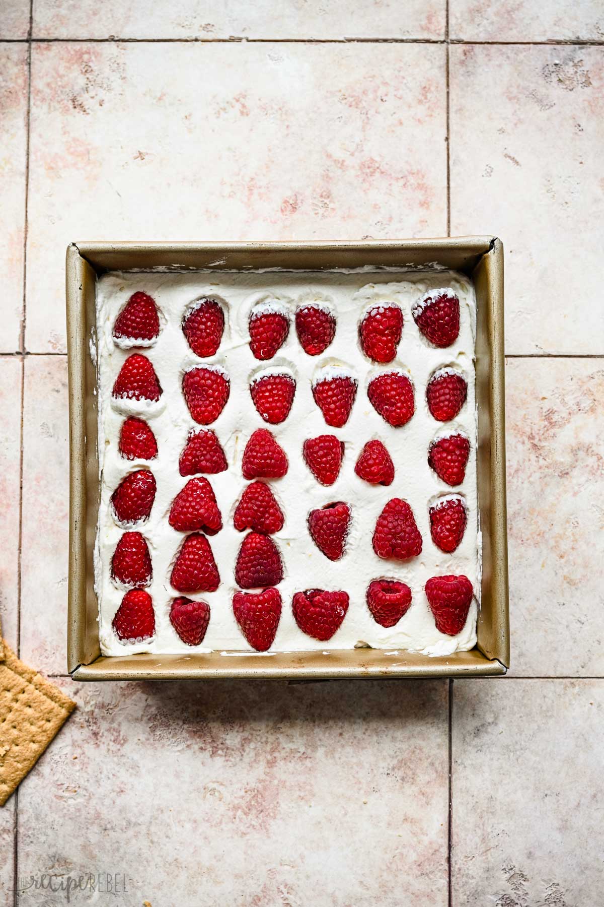 fresh raspberries on top of whipped cream in square pan.