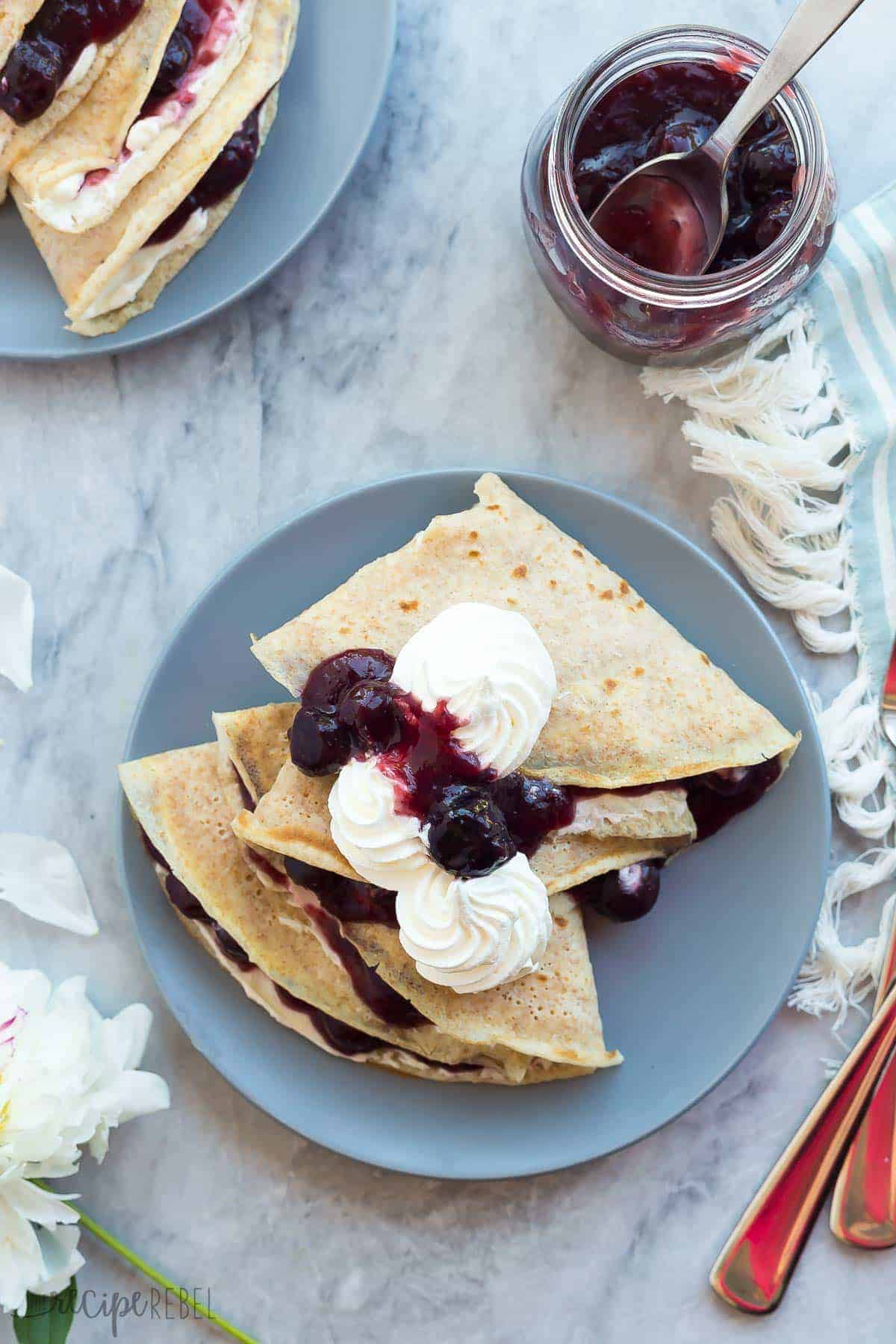 overhead image of cherry cheesecake crepes on grey plate on grey marble background