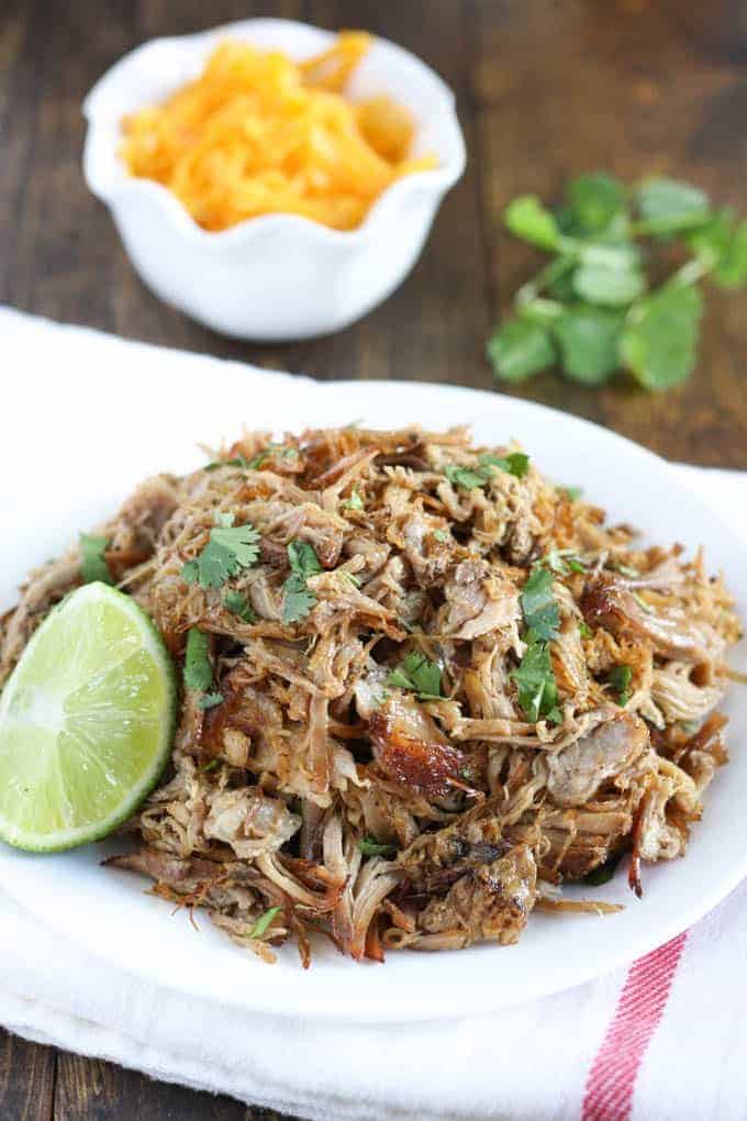These Dump and Go Slow Cooker Recipes require no cooking or browning beforehand -- simply throw it in and walk away! Easy crock pot dump meals for busy weeknights and back to school! Chicken, beef, pork, or vegetarian -- there's something for everyone! #slowcooker #crockpot #dinner #recipes crockpot pork carnitas on white plate with fresh cilantro and lime