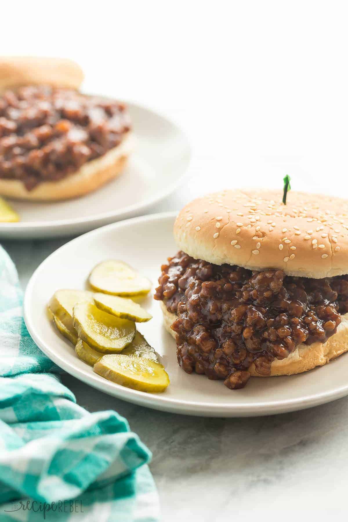 honey garlic turkey sloppy joes on white sesame bun on grey plate with pickles