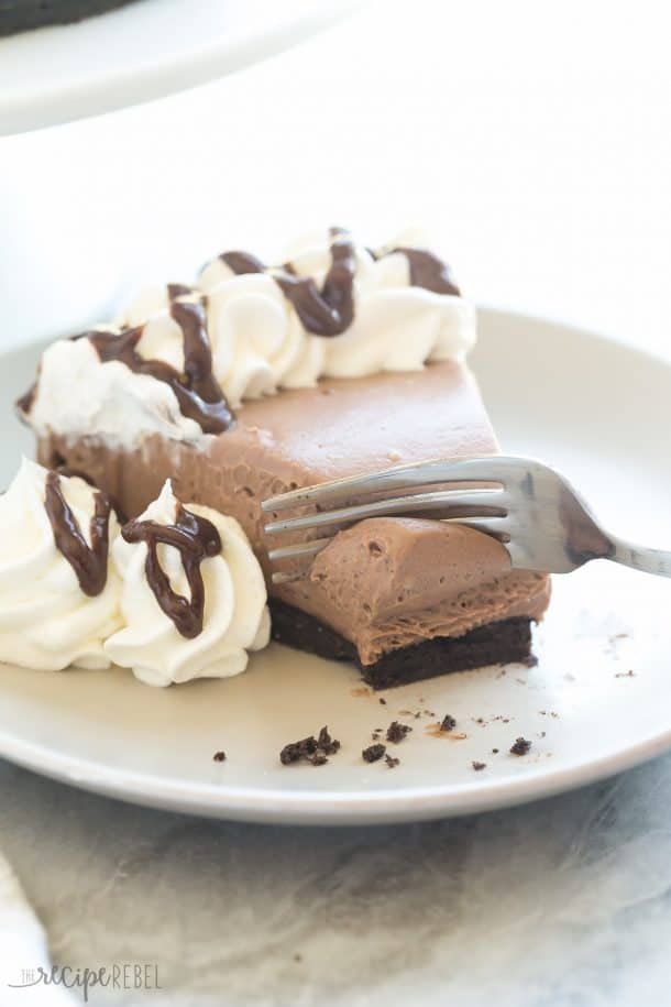 no bake brownie batter cheesecake on white plate with fork taking a bite