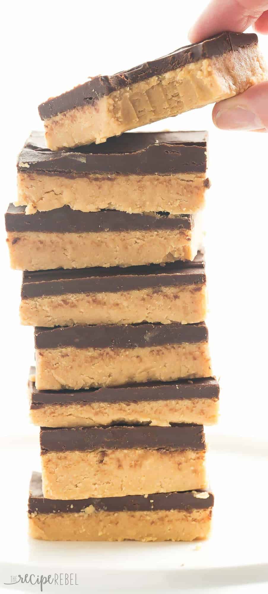 tall stack of no bake chocolate peanut butter bars with hand grabbing top bar