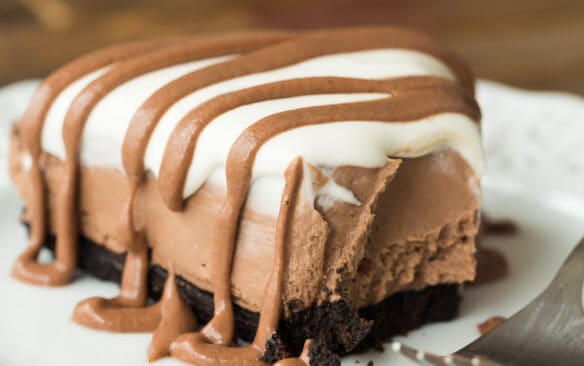 no bake brownie batter piece on white plate with whipped cream and brownie batter drizzle