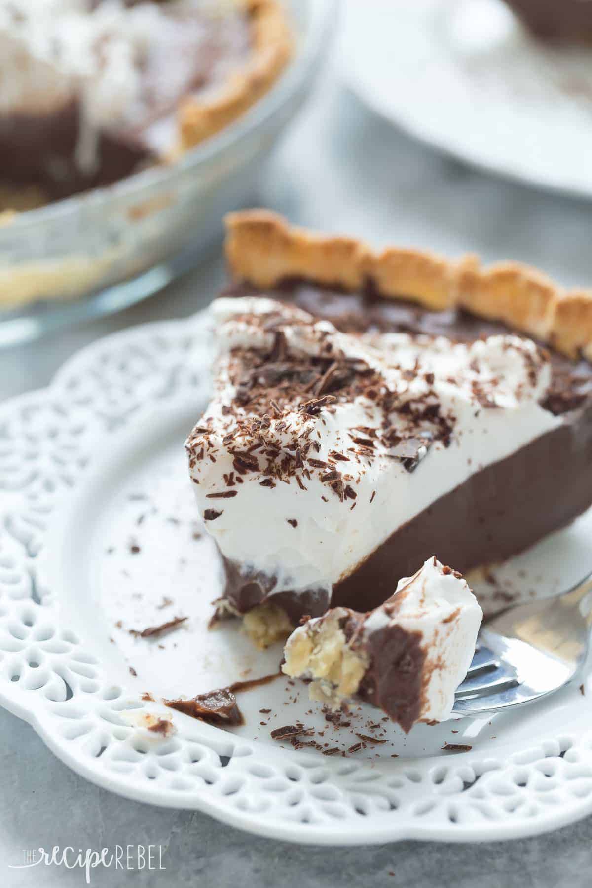 piece of chocolate pie on a white plate with whipped cream and chocolate shavings and bite on fork
